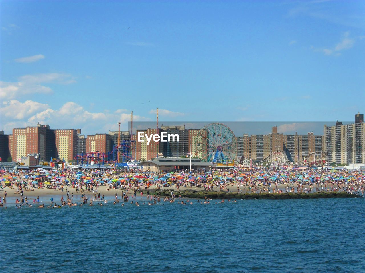 Sea by buildings against blue sky