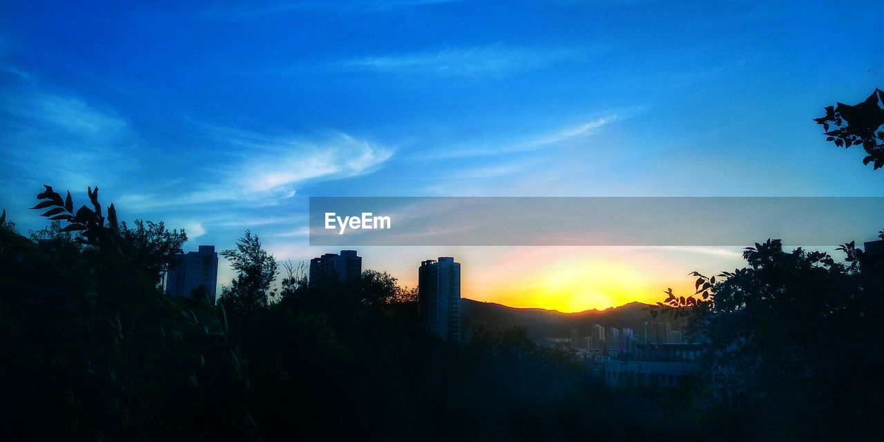 SILHOUETTE BUILDINGS AGAINST BLUE SKY AT SUNSET