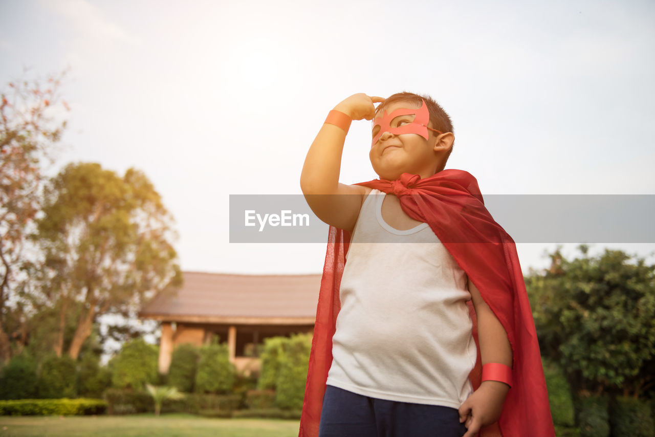 Boy with cape and eye patch playing in park