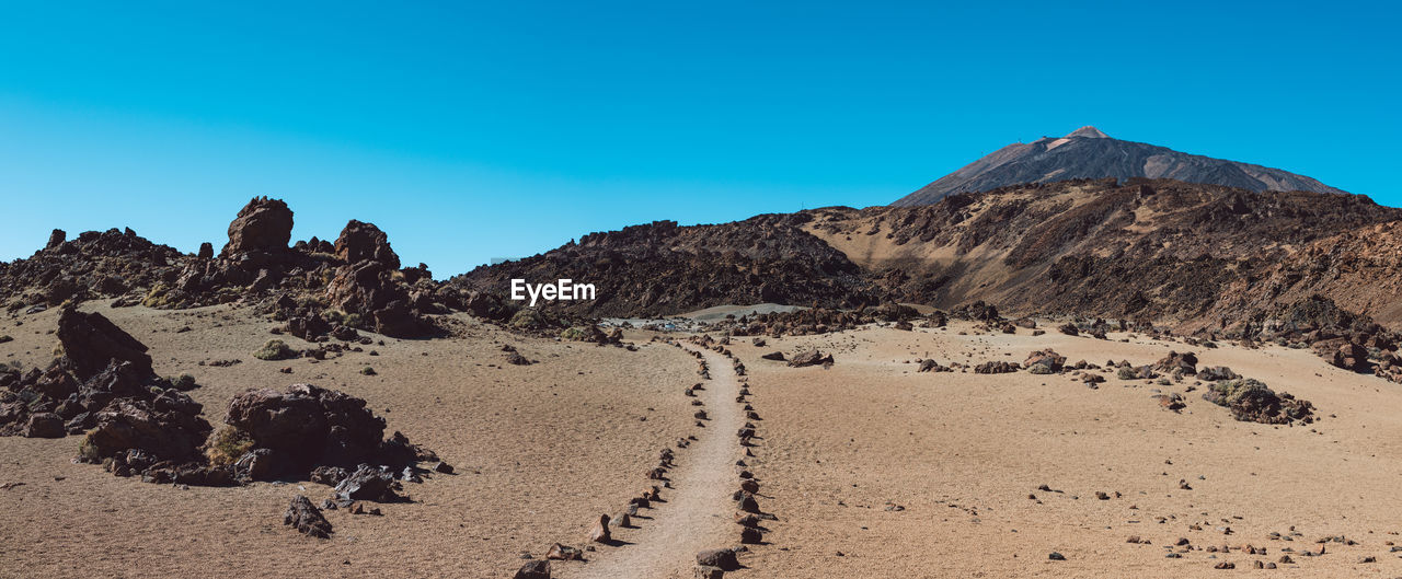 Scenic view of desert against clear blue sky