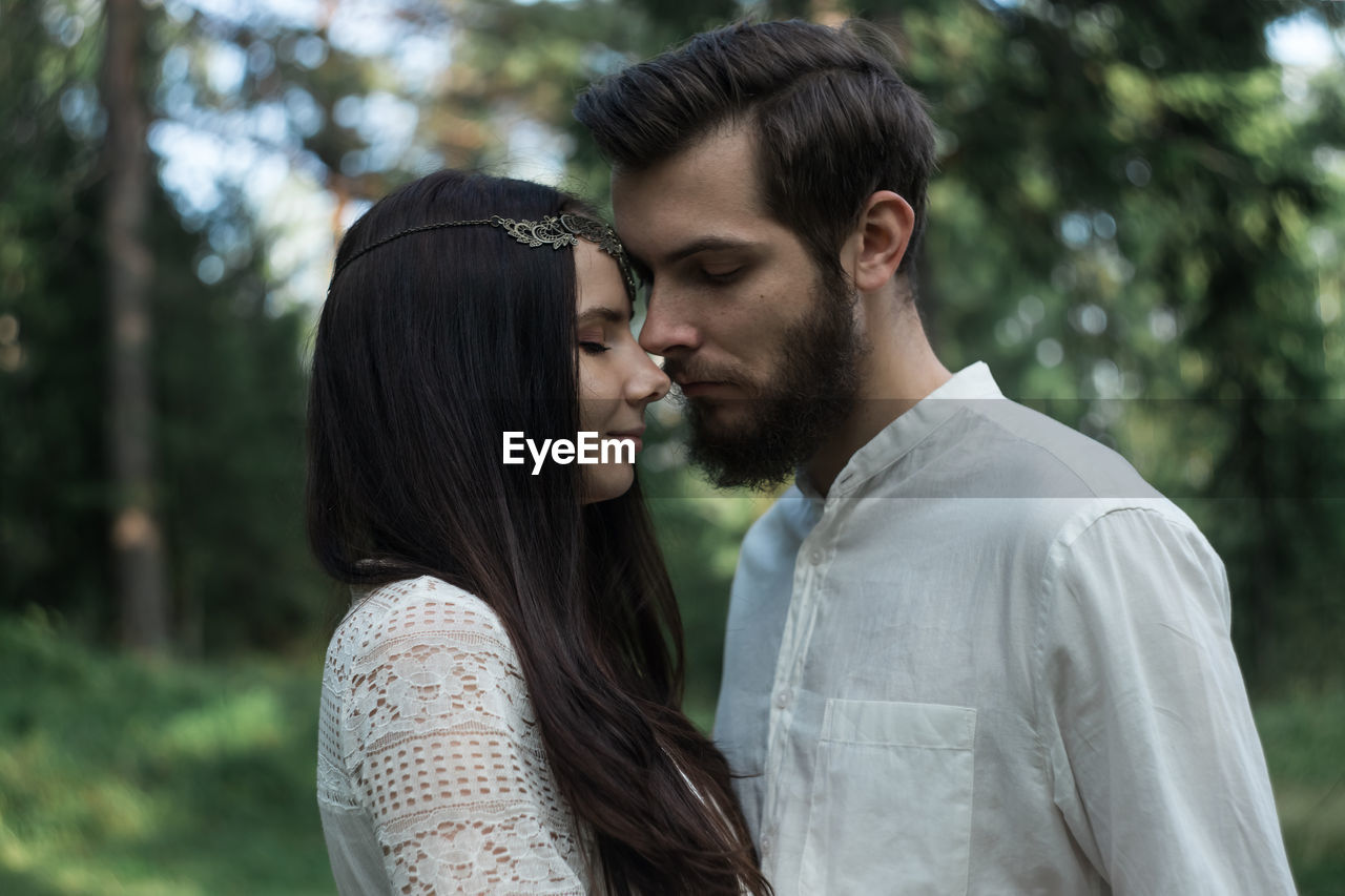 Romantic couple embracing while standing in forest