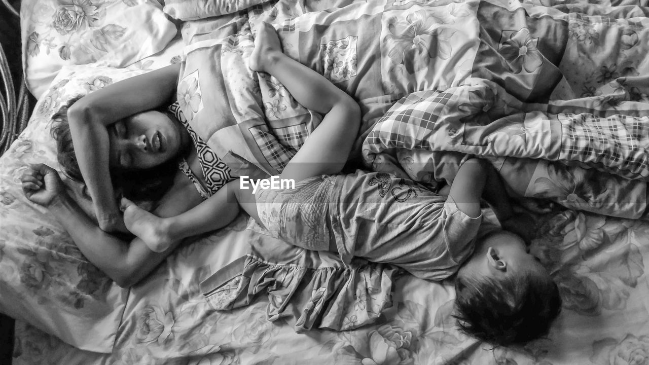 High angle view of mother and son sleeping on bed at home