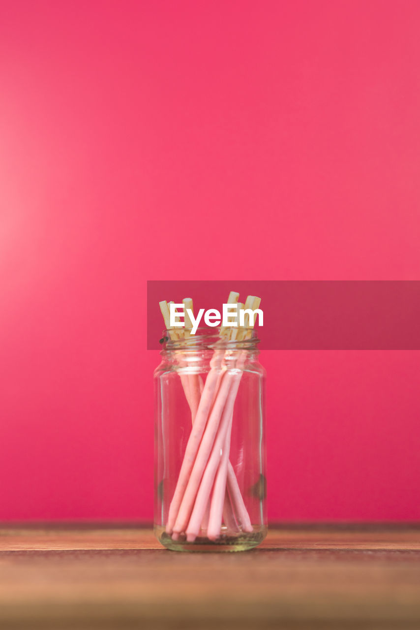 Strawberry dipped stick in a mason jar on a wooden table. concept of sweet food and confectionery