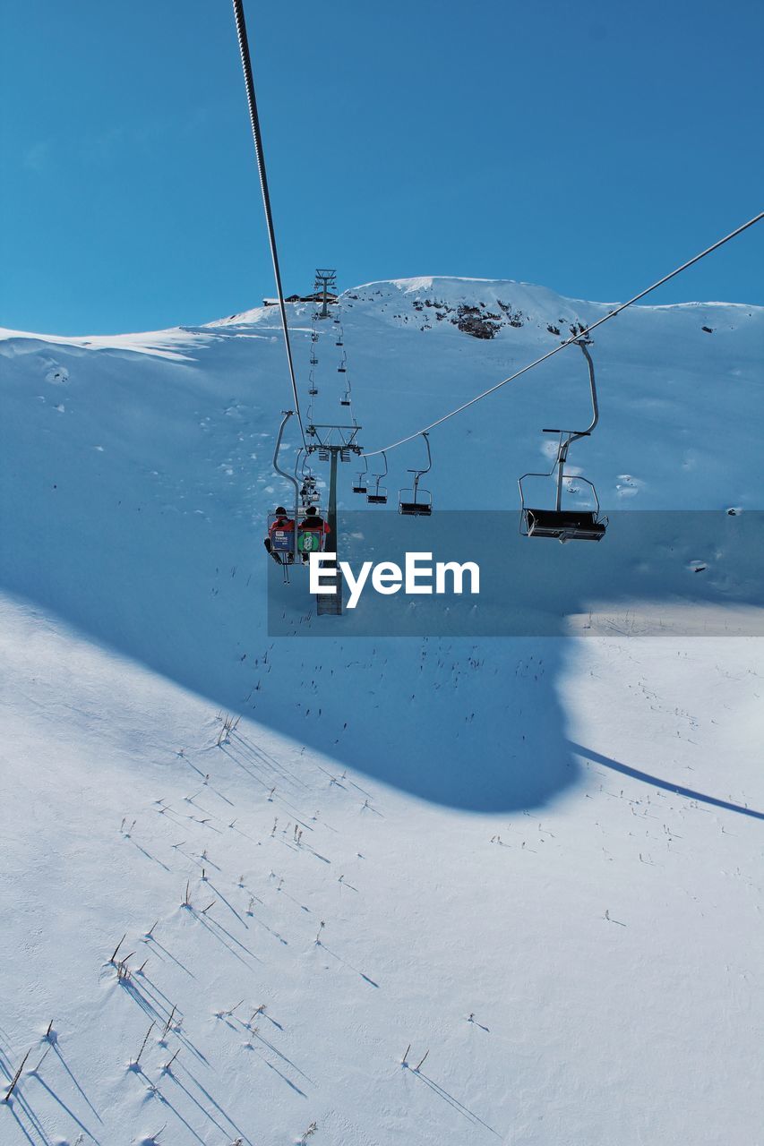 Overhead cable car on snowcapped mountains against sky