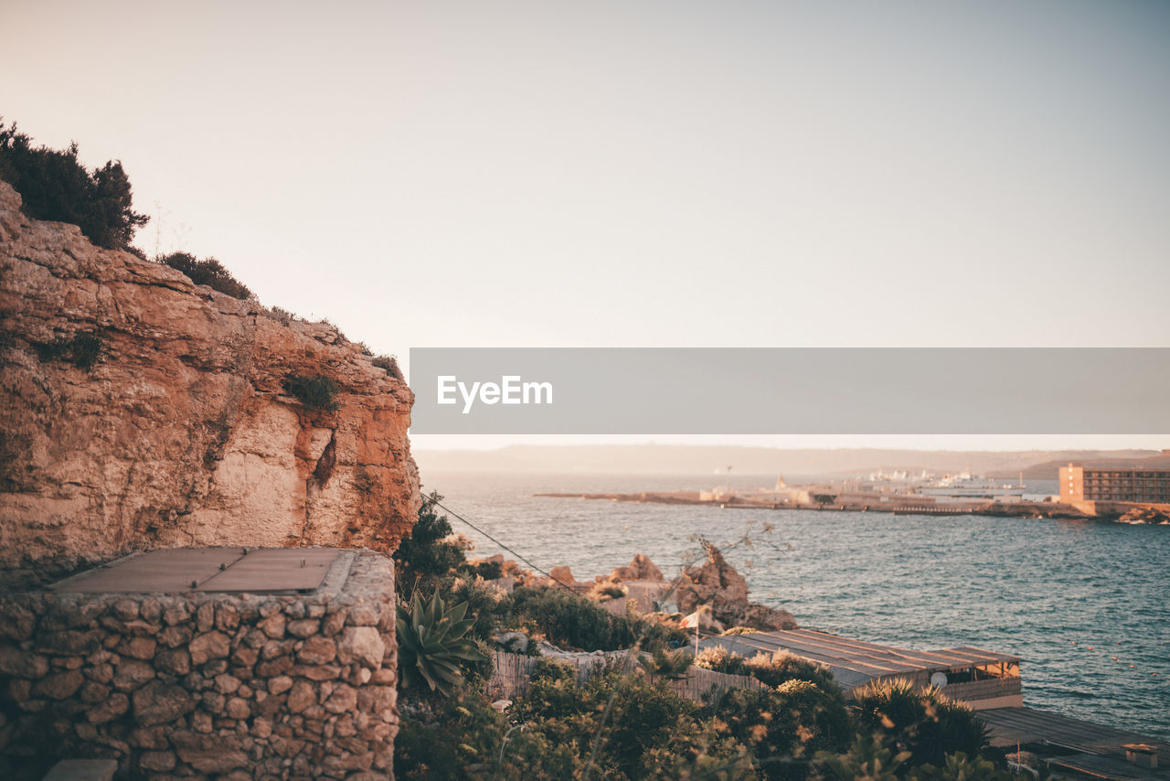 SCENIC VIEW OF ROCKS BY SEA AGAINST CLEAR SKY