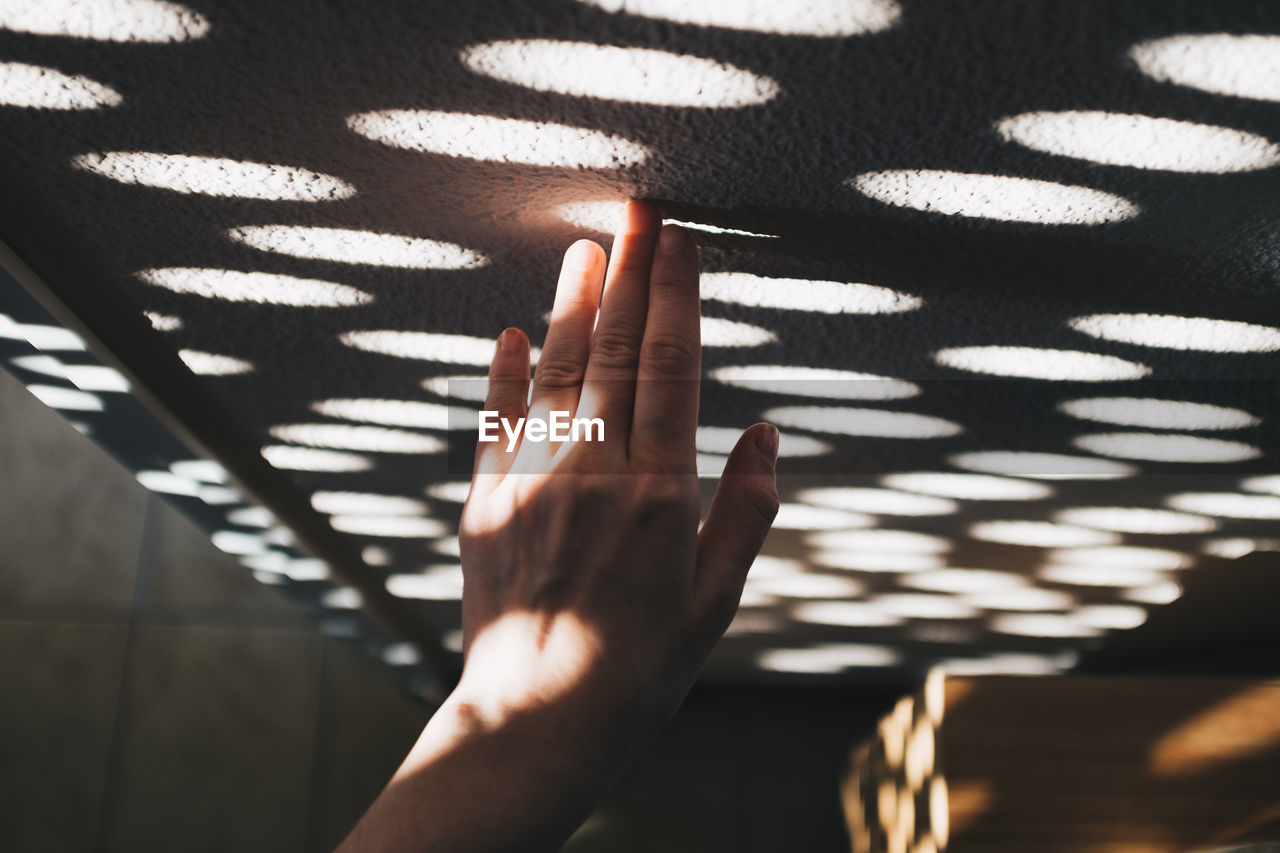 Hand touching pattern made by sunlight on wall