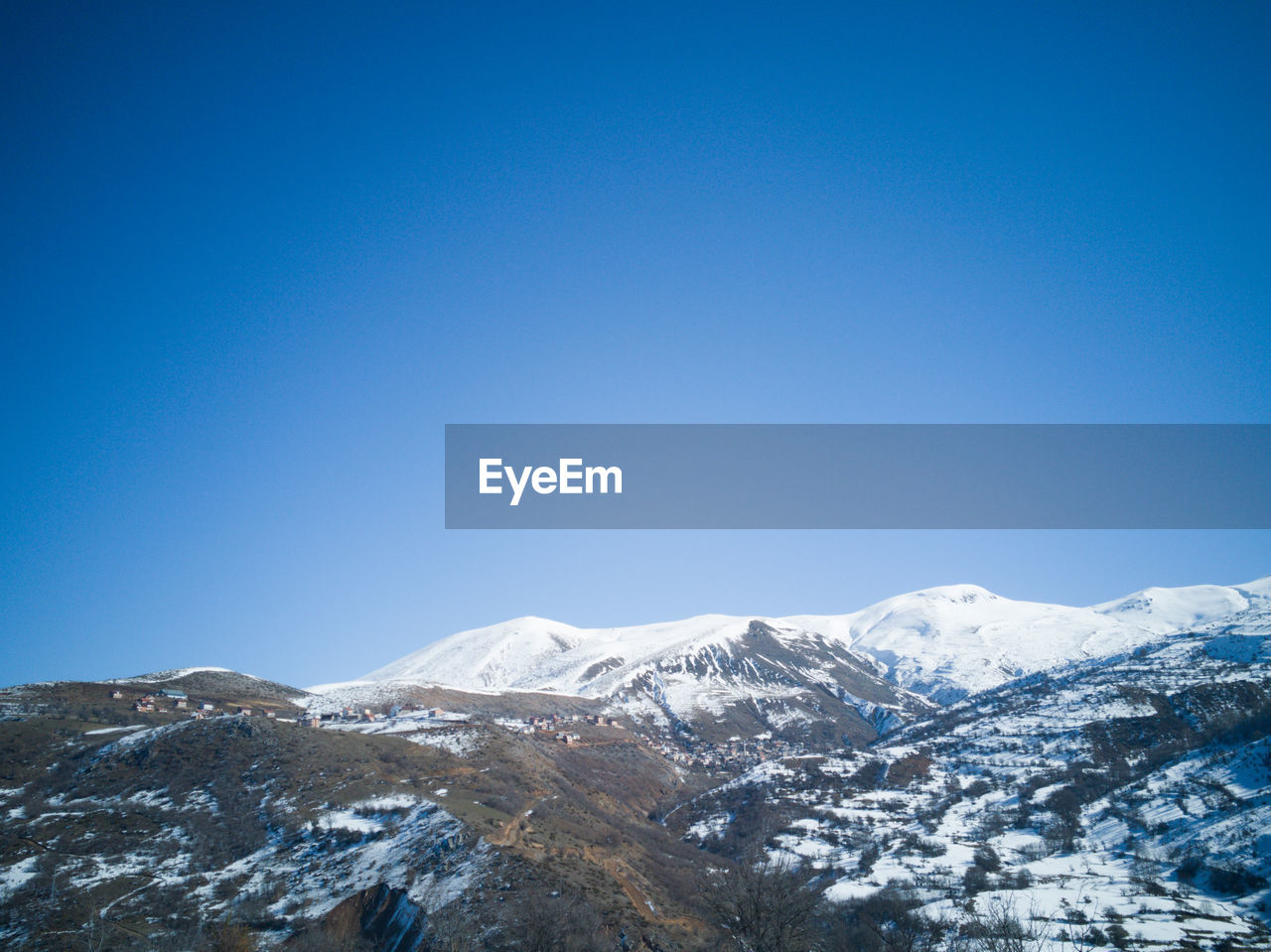 Scenic view of snowcapped mountains against clear blue sky