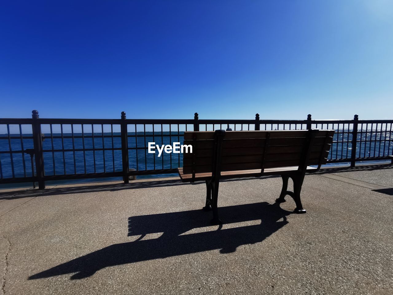 SHADOW OF PEOPLE ON RAILING AGAINST CLEAR BLUE SKY