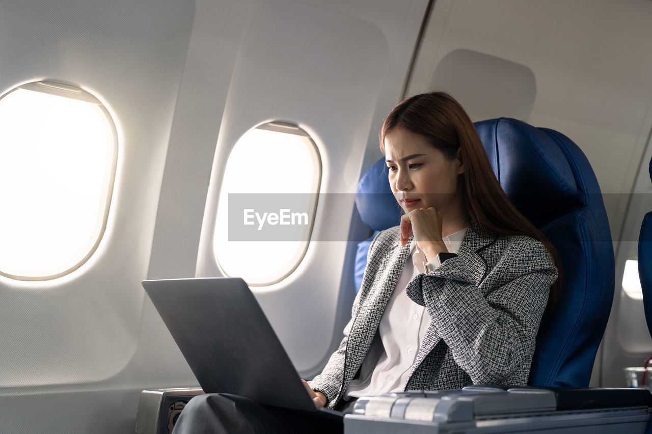 Businesswoman using laptop in airplane