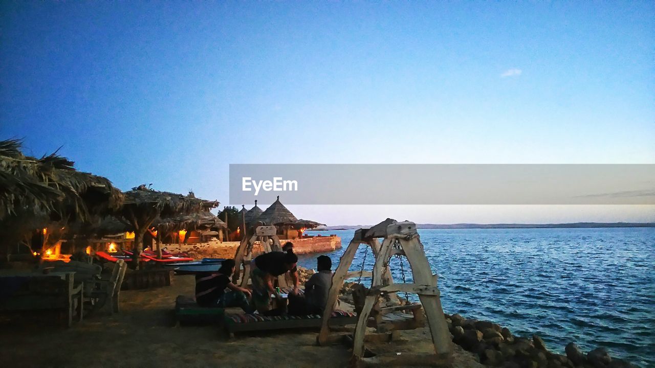 DECK CHAIRS ON BEACH AGAINST CLEAR SKY