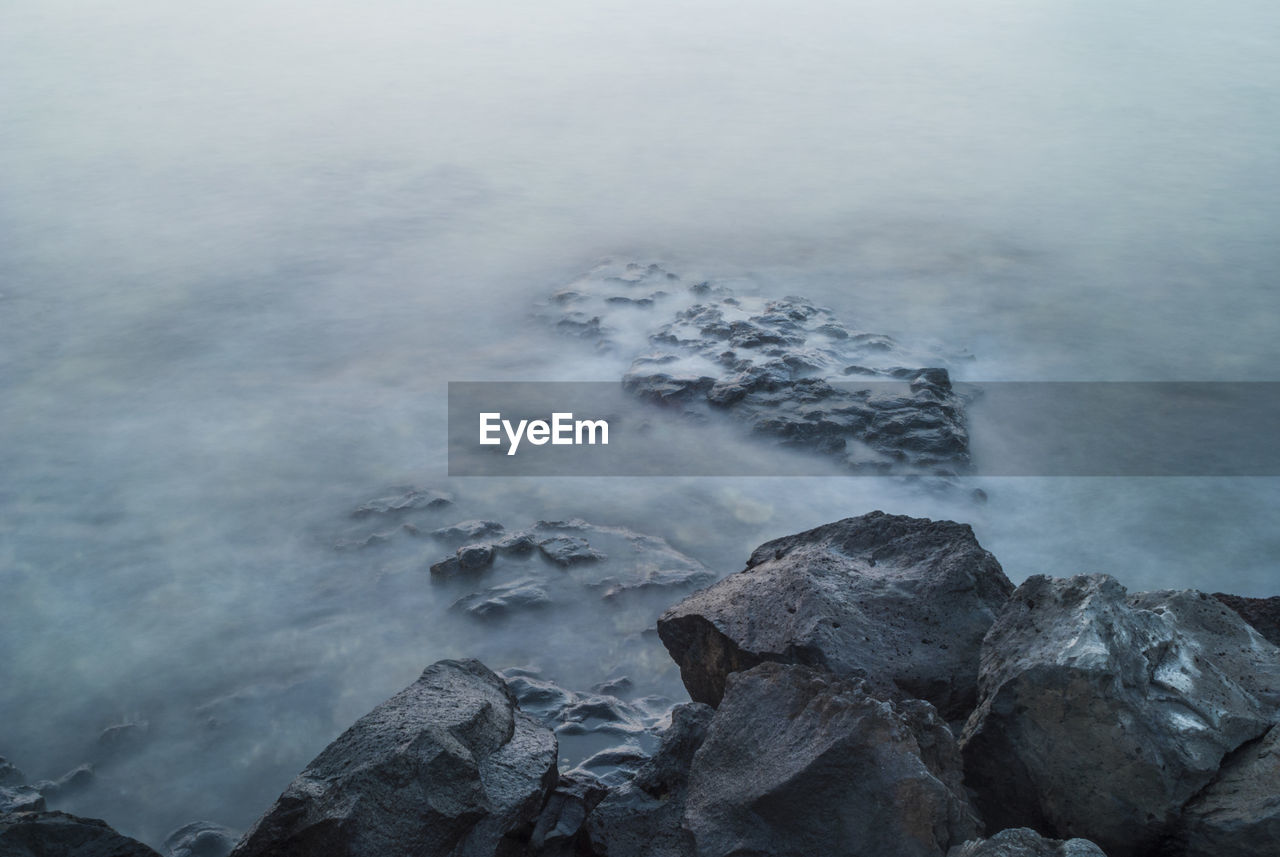 High angle view of rocky shore during foggy weather