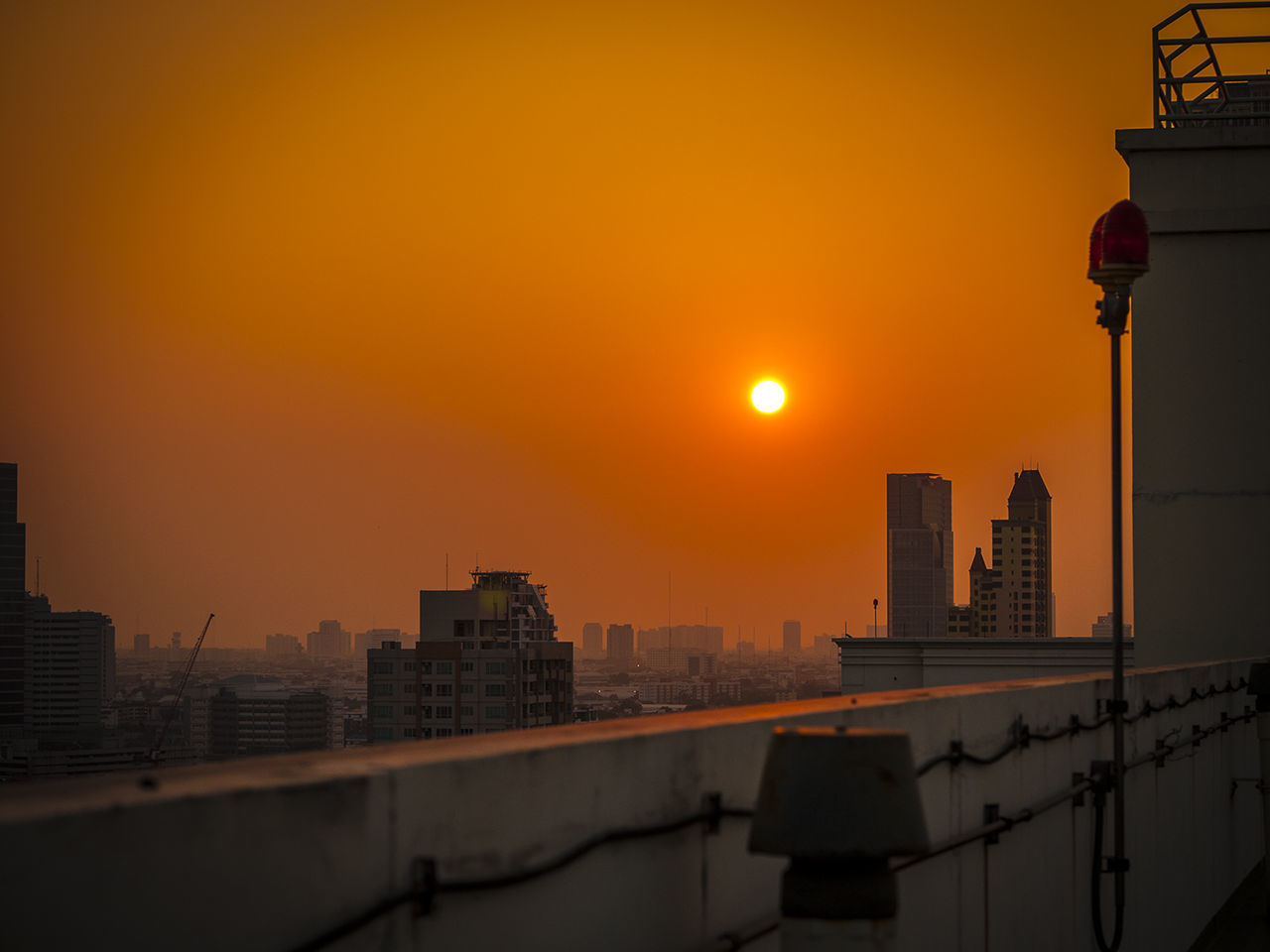 Illuminated cityscape against sky during sunset seen through terrace