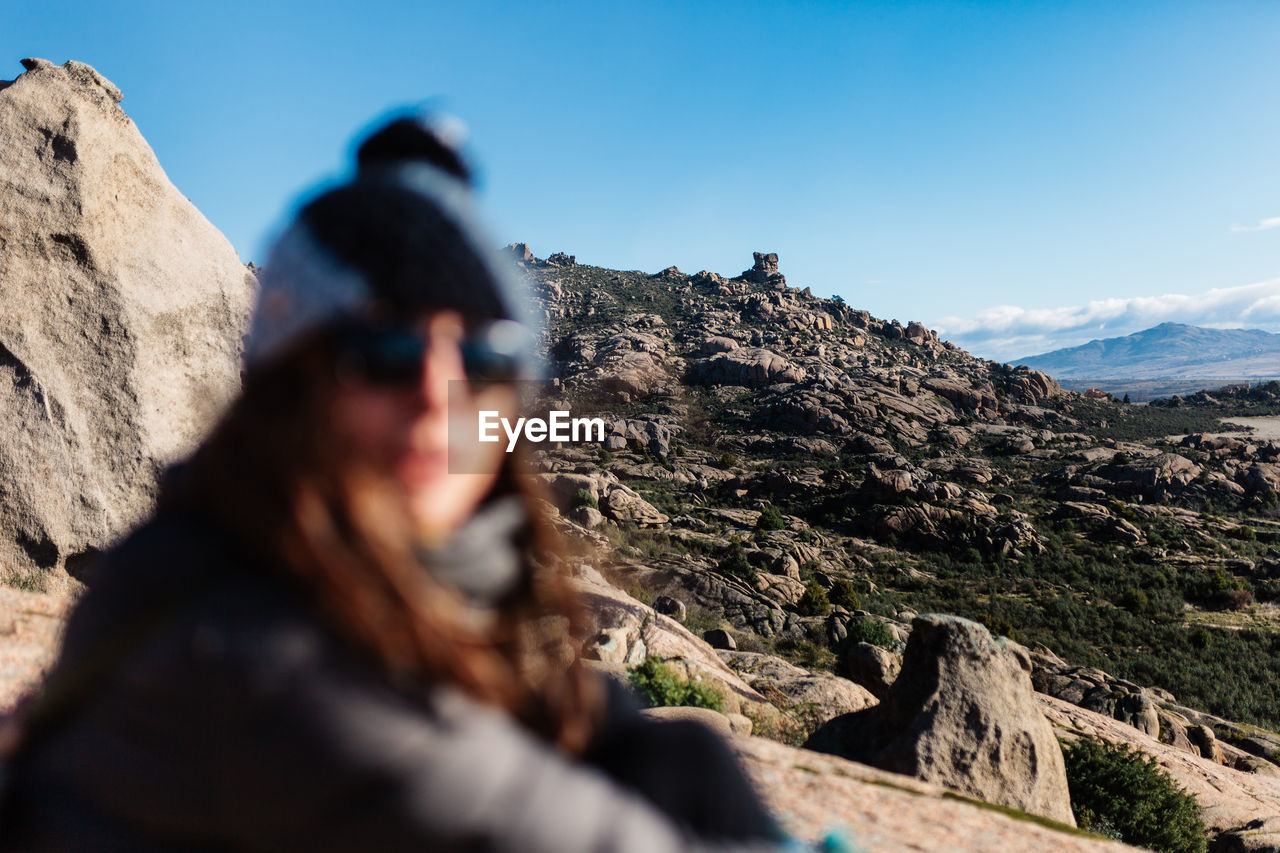 Man on rock by mountains against sky