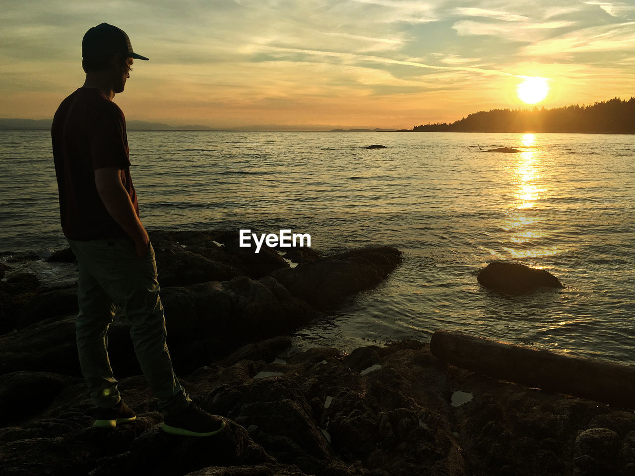 Man standing by sea against sky during sunset