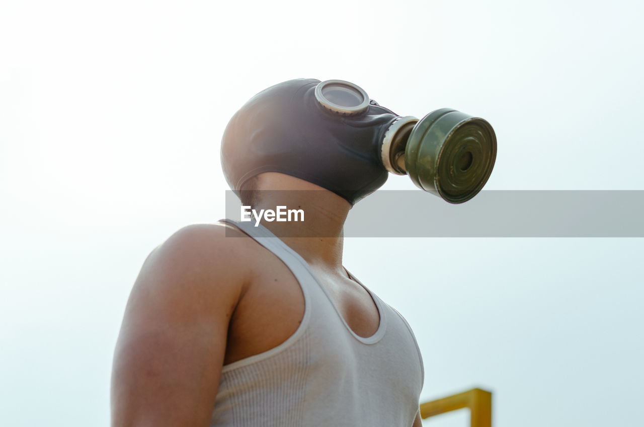 Low angle view of man wearing gas mask against sky