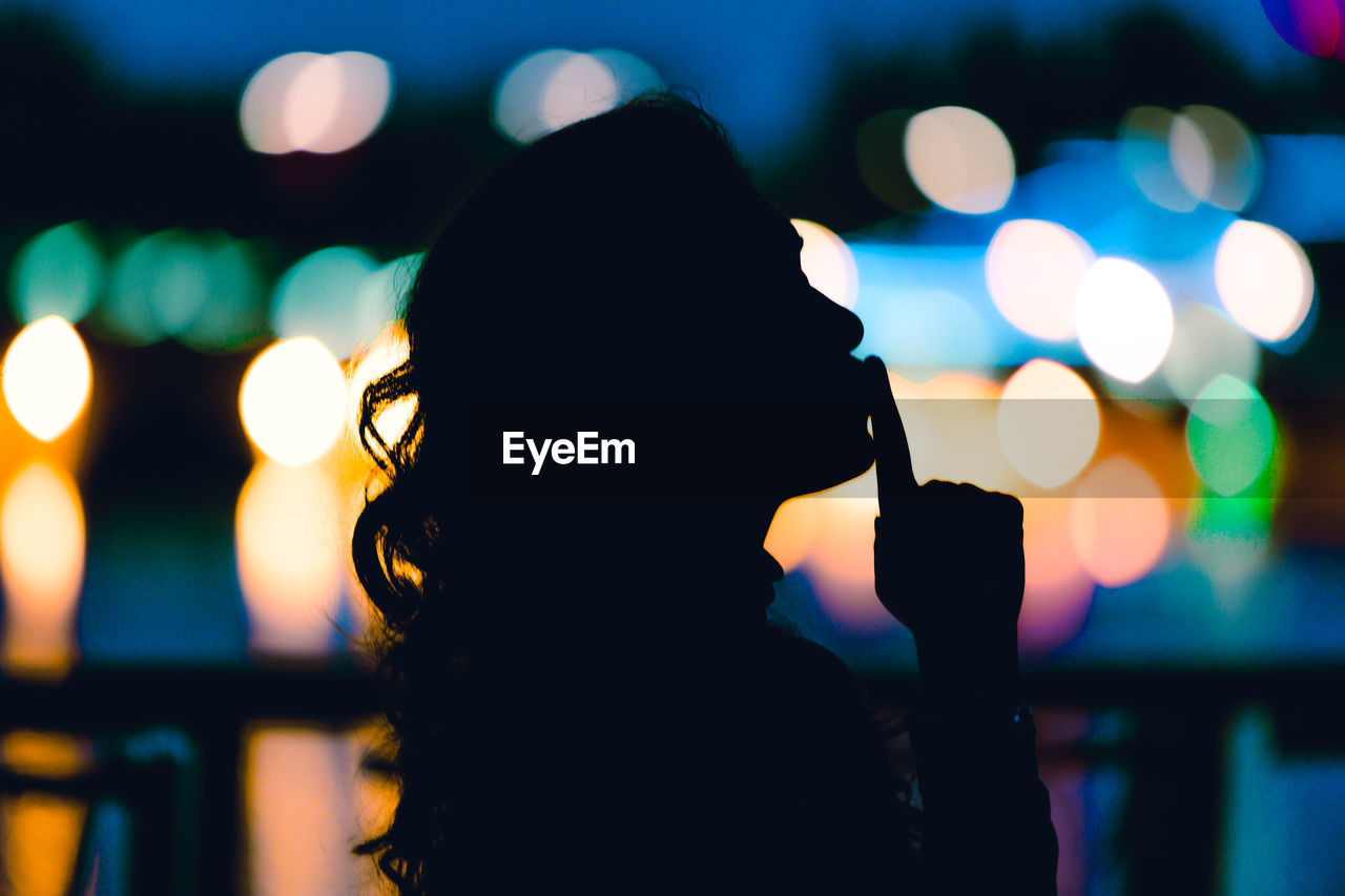 DEFOCUSED IMAGE OF MAN PHOTOGRAPHING ILLUMINATED LIGHTS