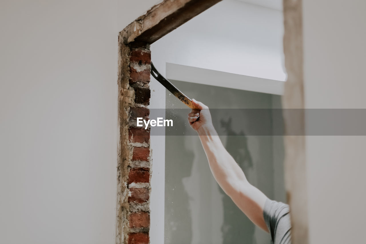 A man working with a crowbar in a doorway.