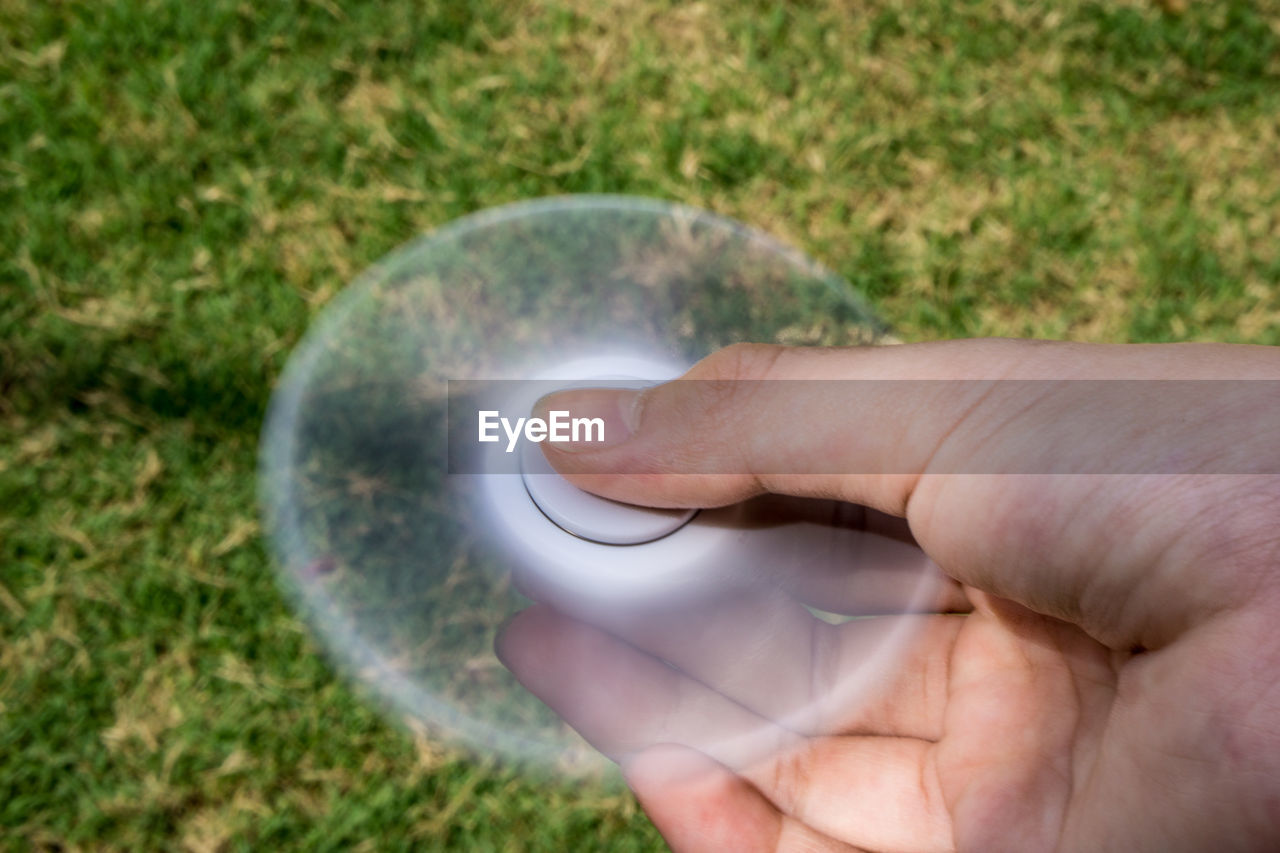 Close-up of cropped hand holding spinning fidget spinner