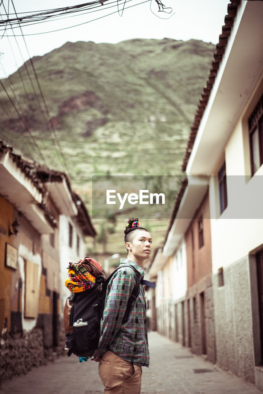 Portrait of funky female traveler with back pack and colourful fabric