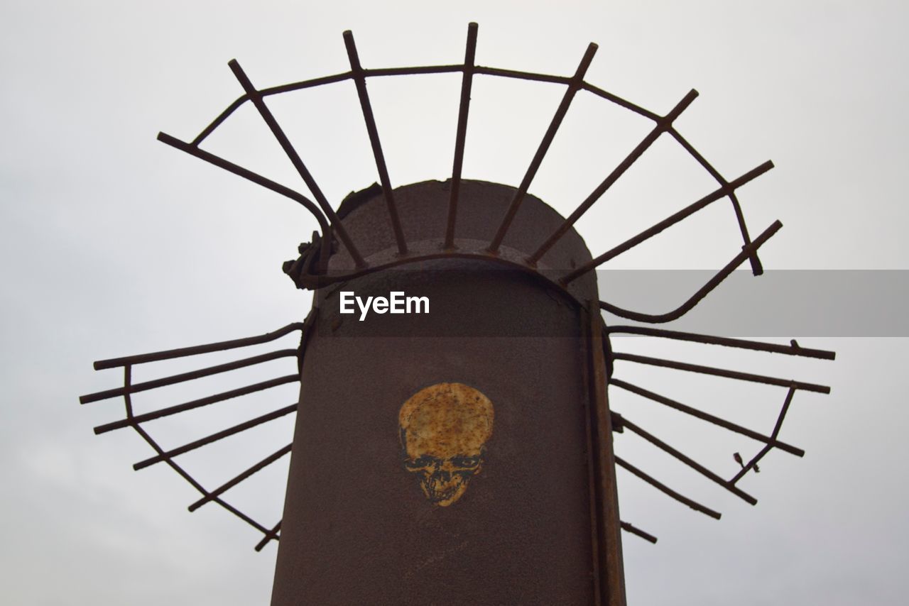 Low angle view of skull art on abandoned pole against clear sky