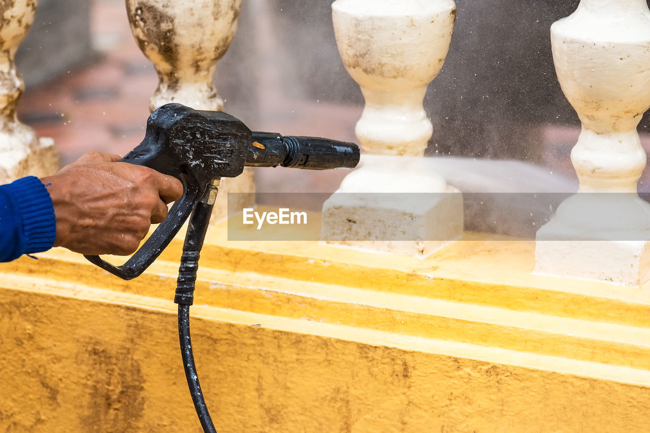 Man cleaning balustrade with water spray 