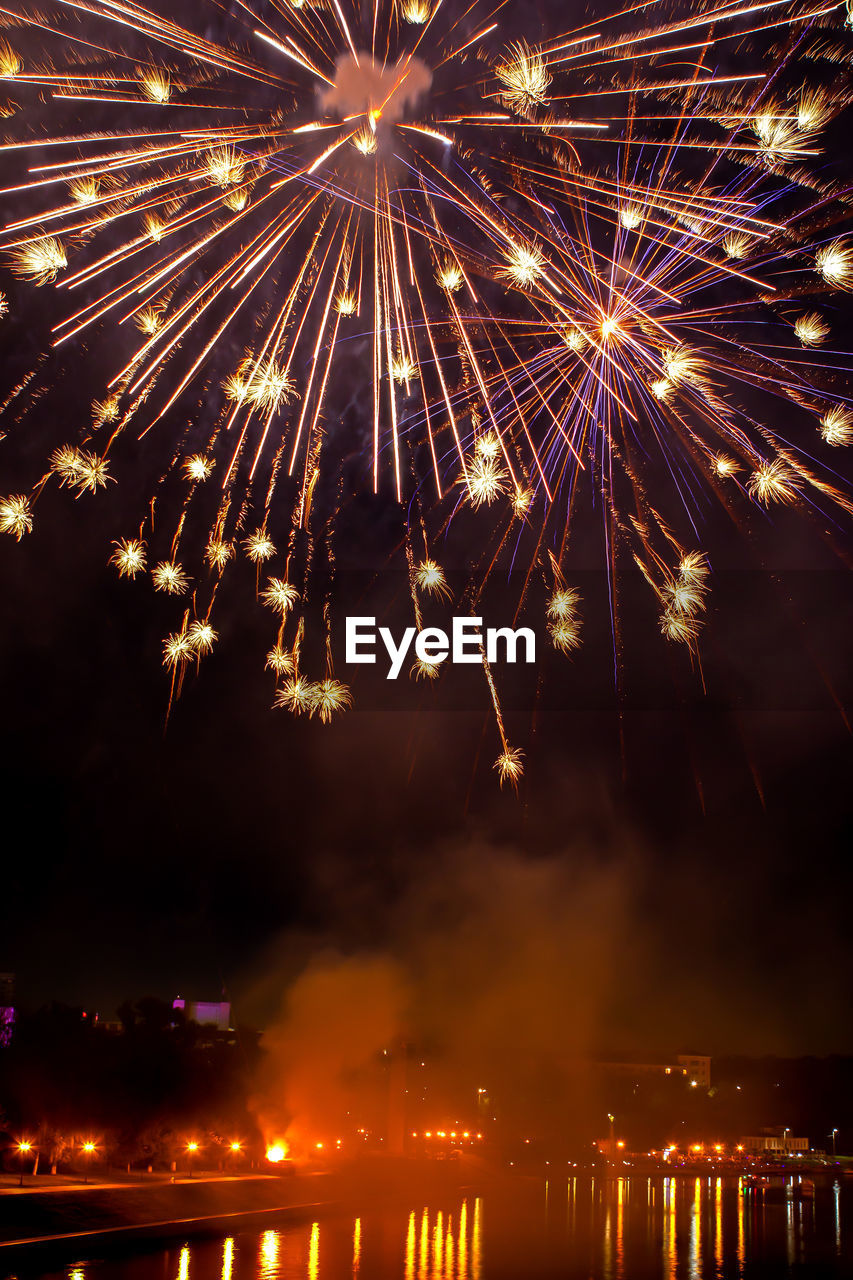 Fireworks in evening sky over river in city. holiday concept. close-up, vertical position of frame