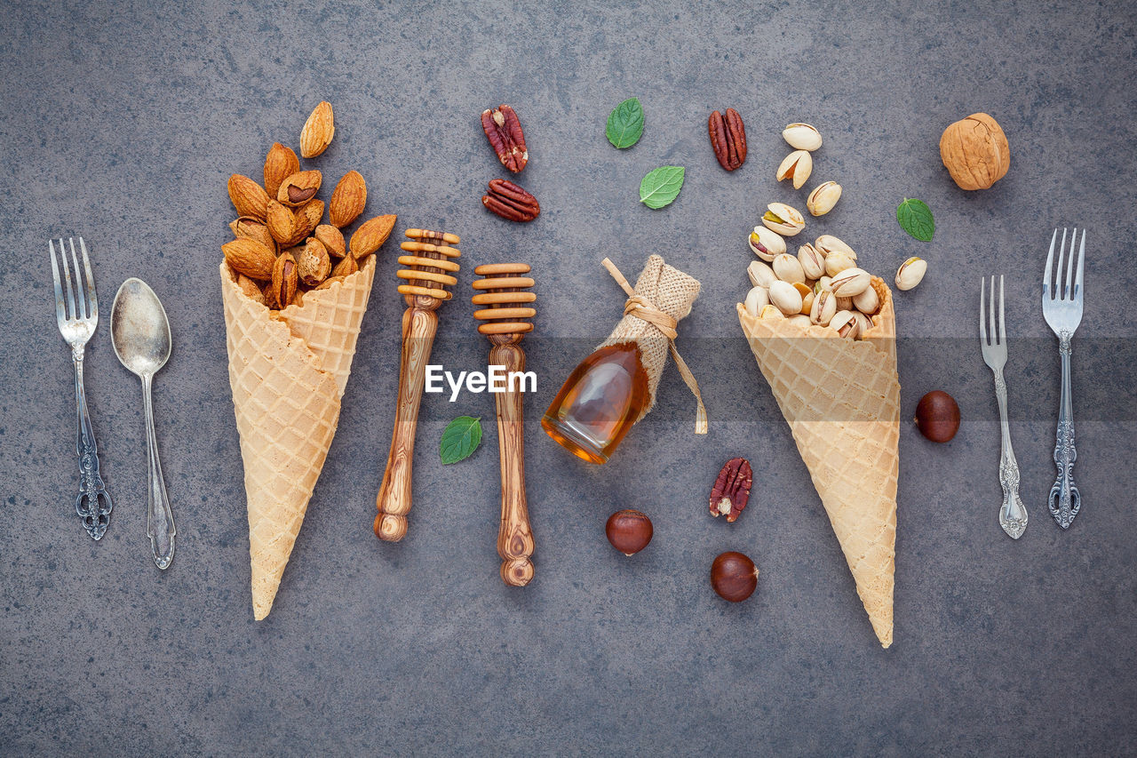 High angle view of ice cream cones with nuts and cutlery on wooden table