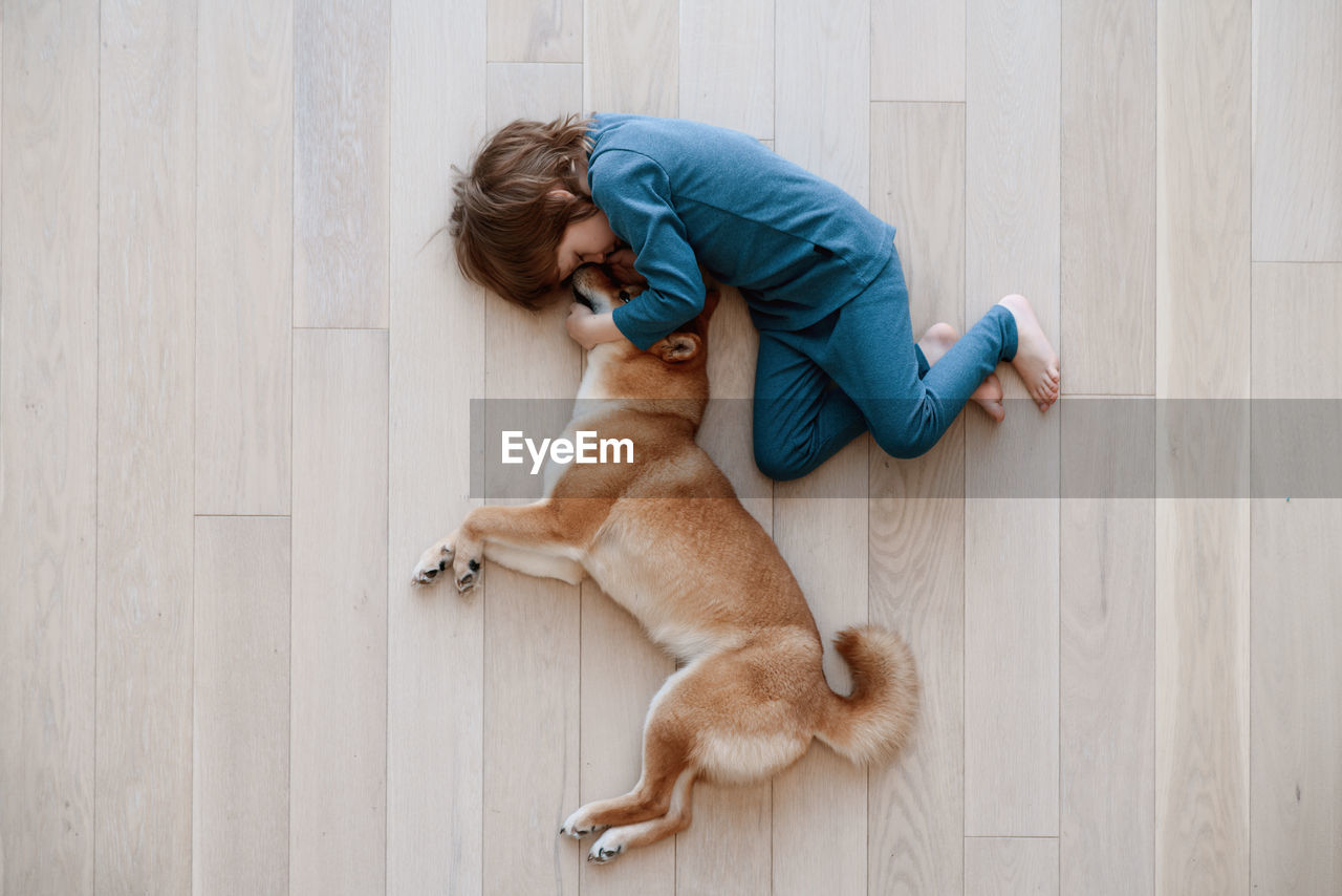 HIGH ANGLE VIEW OF WOMAN AND CAT ON WOODEN FLOOR