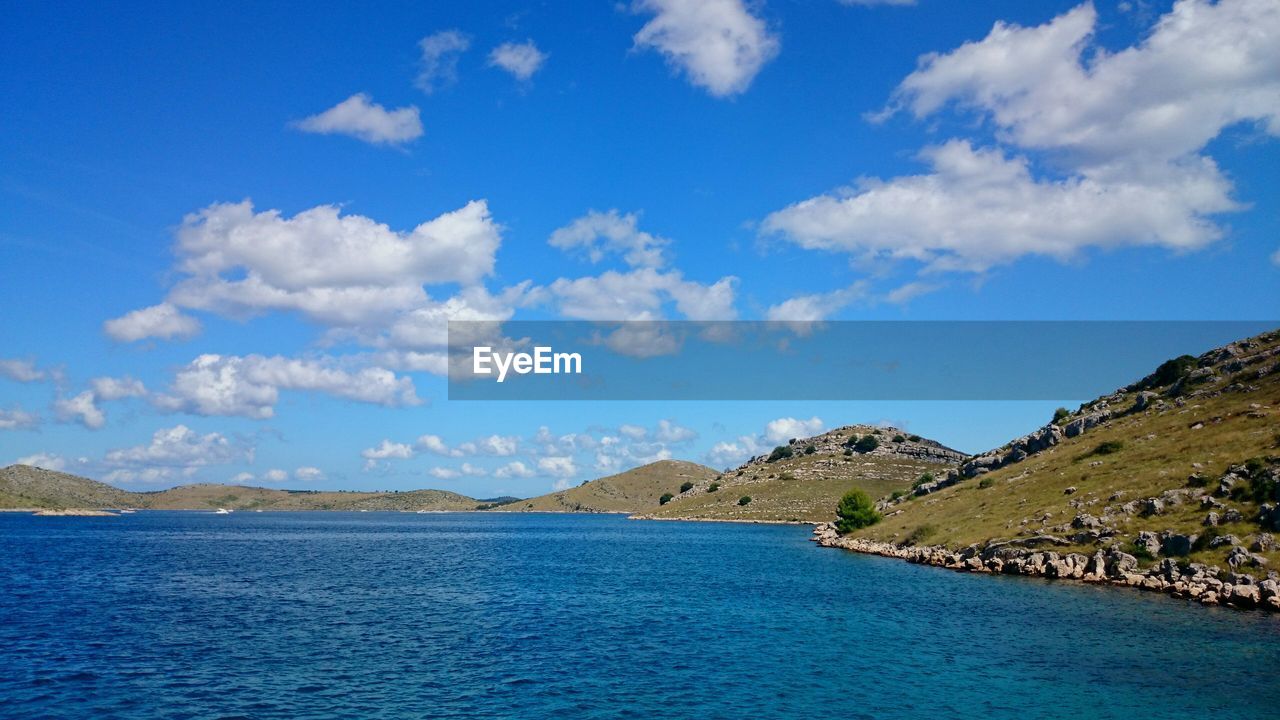 Scenic view of lake by mountains against blue sky