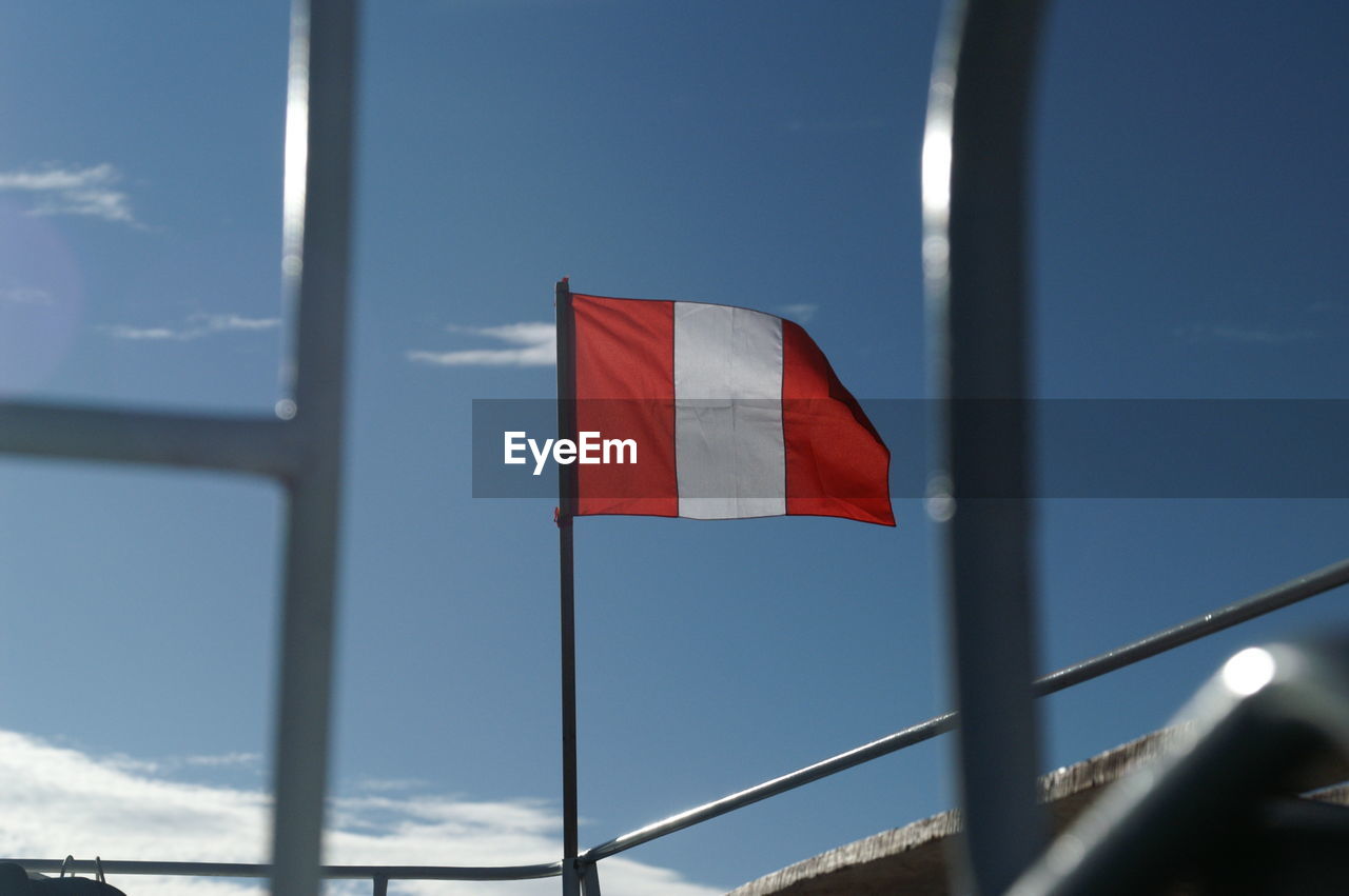 LOW ANGLE VIEW OF RED FLAG AGAINST SKY