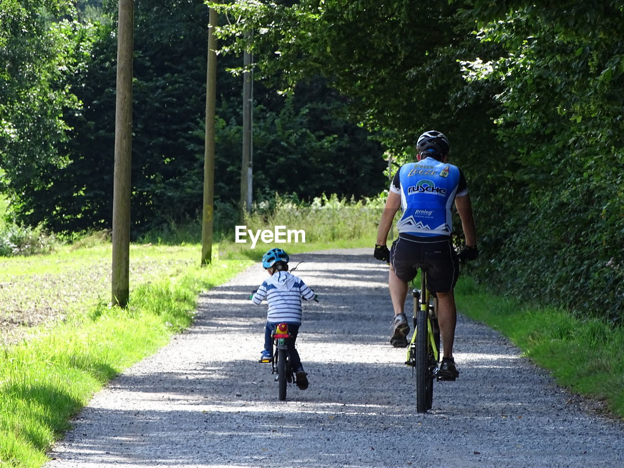 REAR VIEW OF PEOPLE RIDING BICYCLE ON ROAD