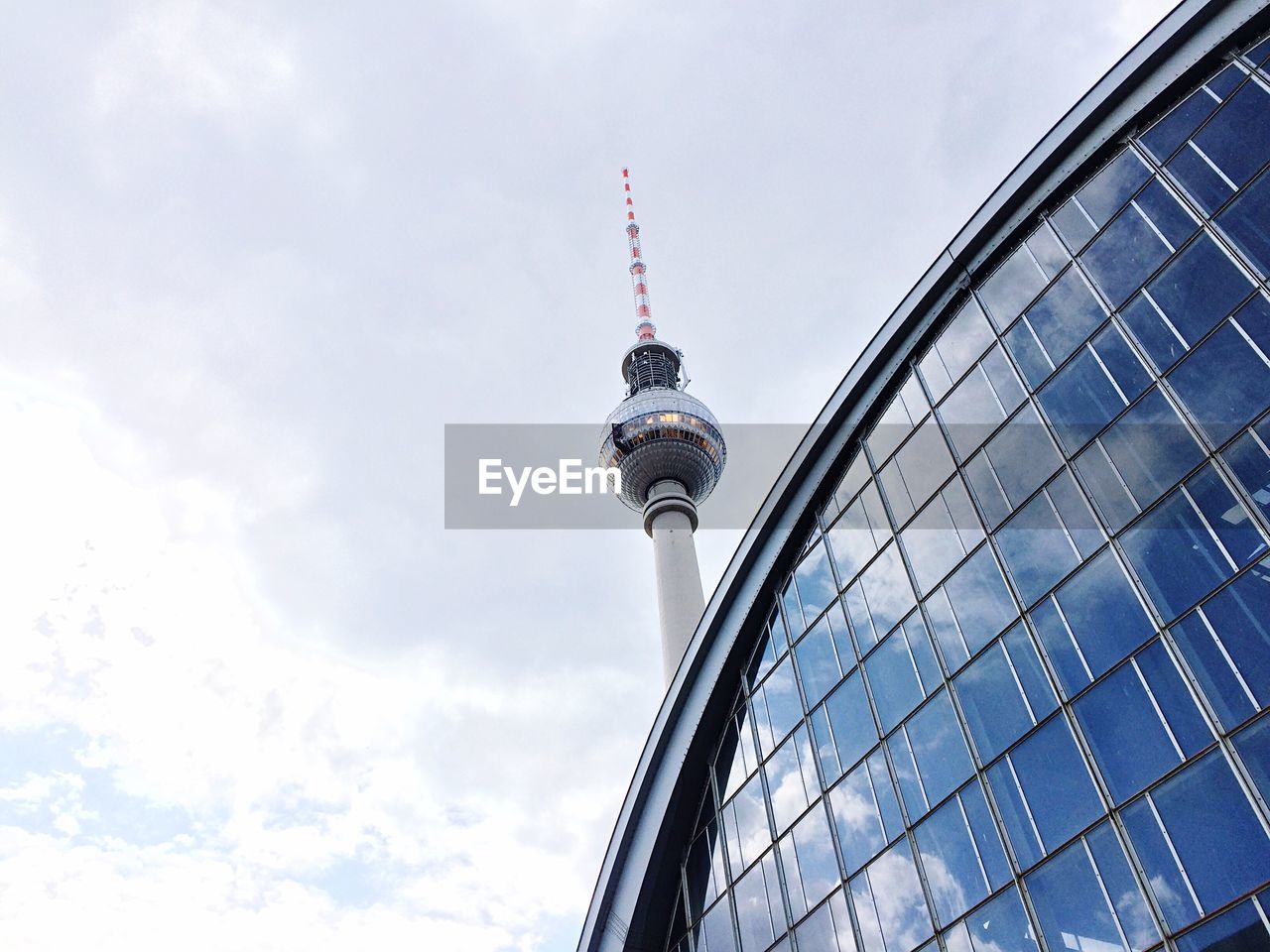 Low angle view of fernsehturm against cloudy sky