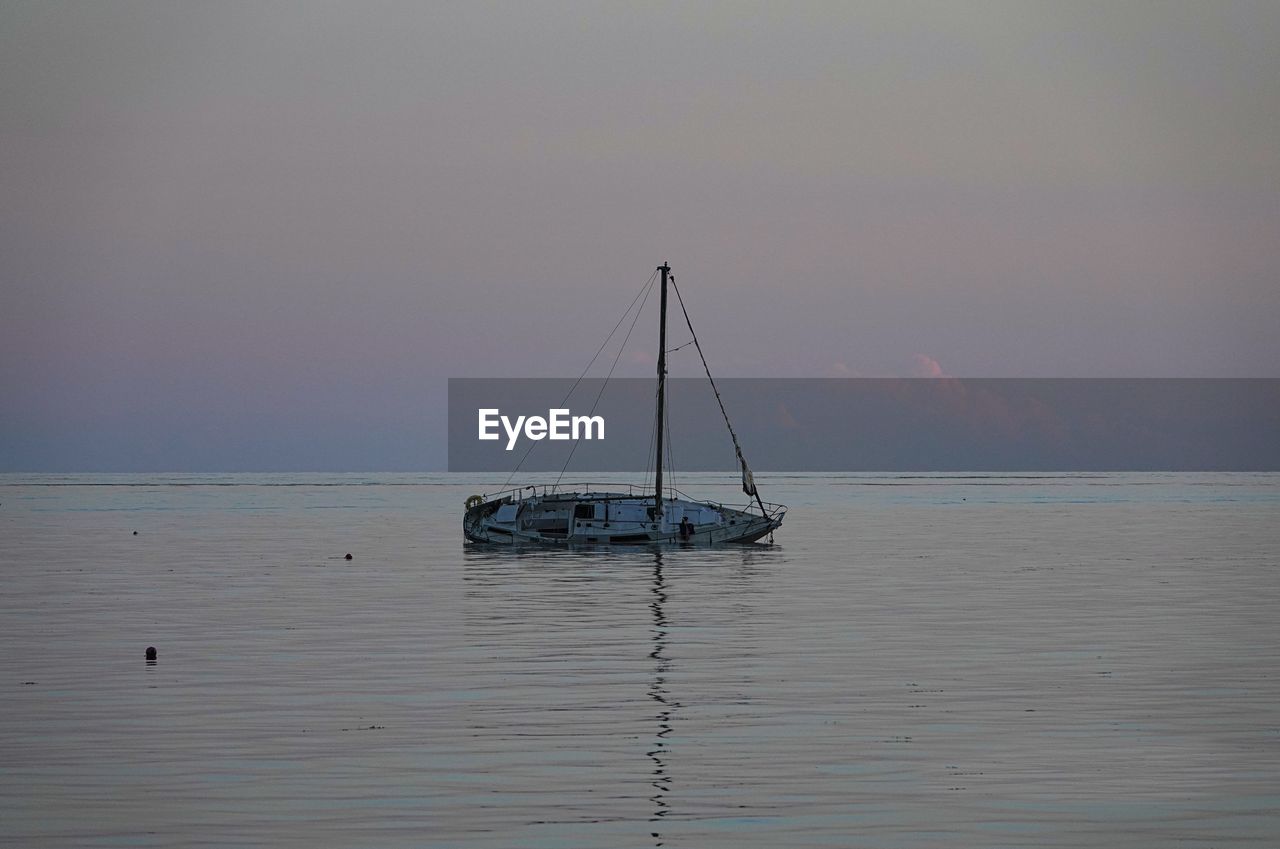 water, sea, nautical vessel, transportation, sky, sailboat, mode of transportation, beauty in nature, ship, nature, boat, sailing, tranquility, scenics - nature, ocean, sunset, tranquil scene, travel, horizon, horizon over water, vehicle, bay, shore, idyllic, pole, no people, watercraft, mast, reflection, sailing ship, outdoors, seascape, environment, travel destinations, beach, non-urban scene, coast, land, tourism, holiday, vacation, dusk, cloud, trip, day