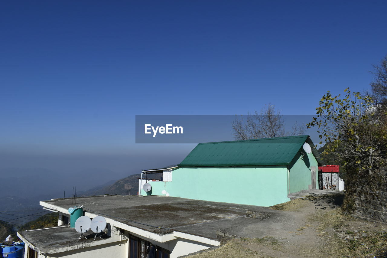 architecture, sky, built structure, building exterior, house, nature, building, blue, clear sky, no people, water, day, mountain, roof, outdoors, land, sea, residential district, plant, environment, hut, copy space, beach, tree, scenics - nature, sunny