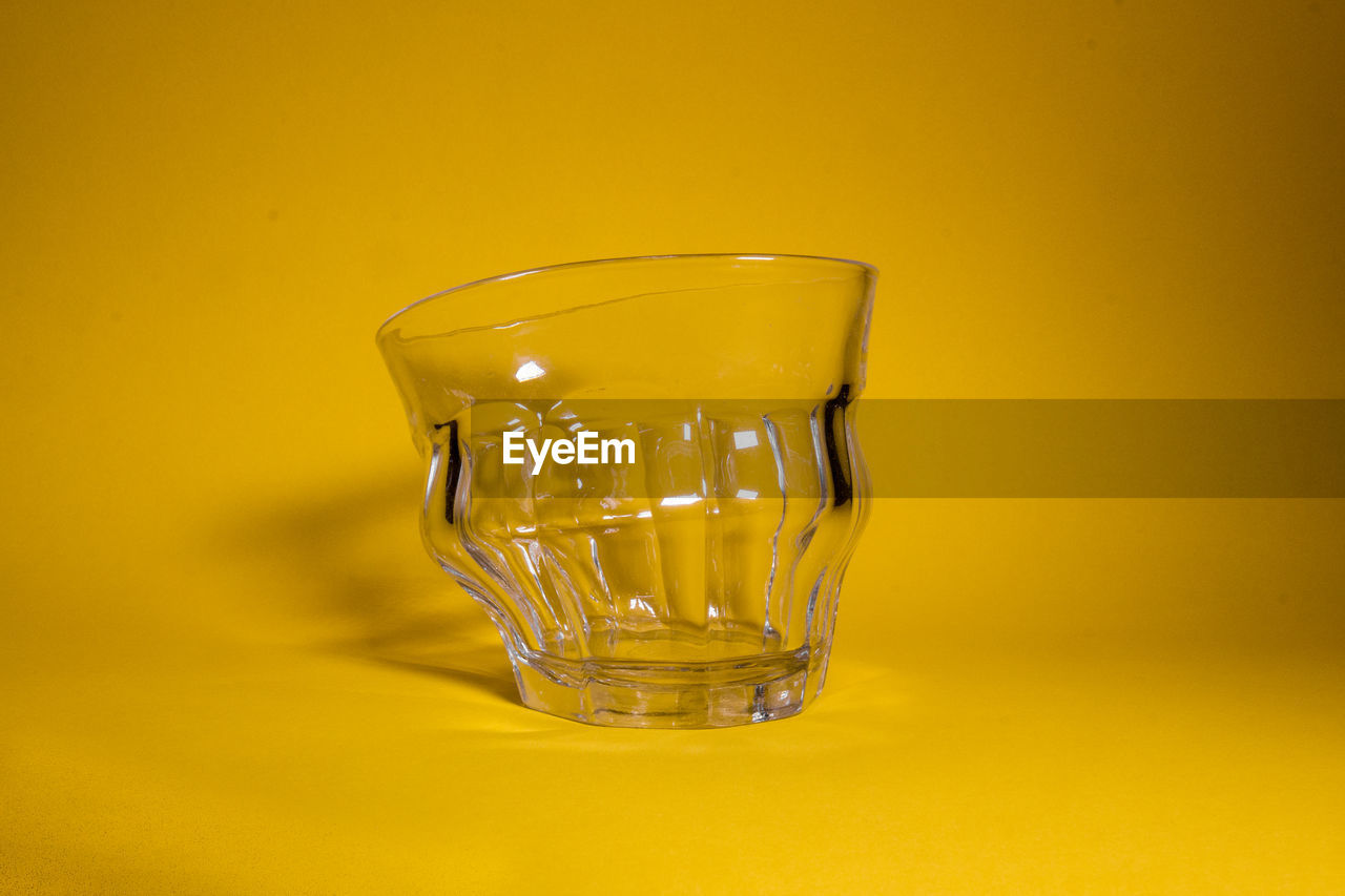 Close-up of drinking glass against yellow background