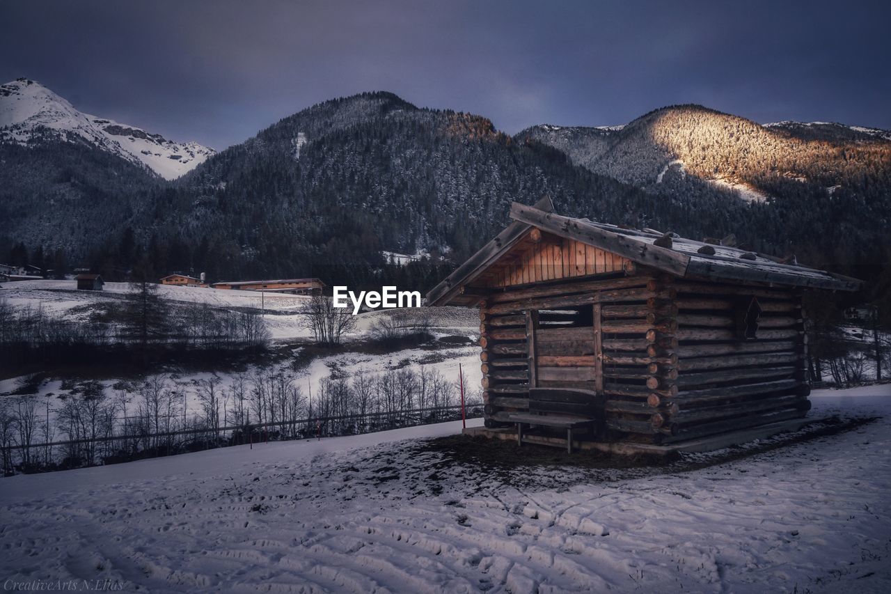 HOUSES ON SNOW COVERED FIELD AGAINST SKY