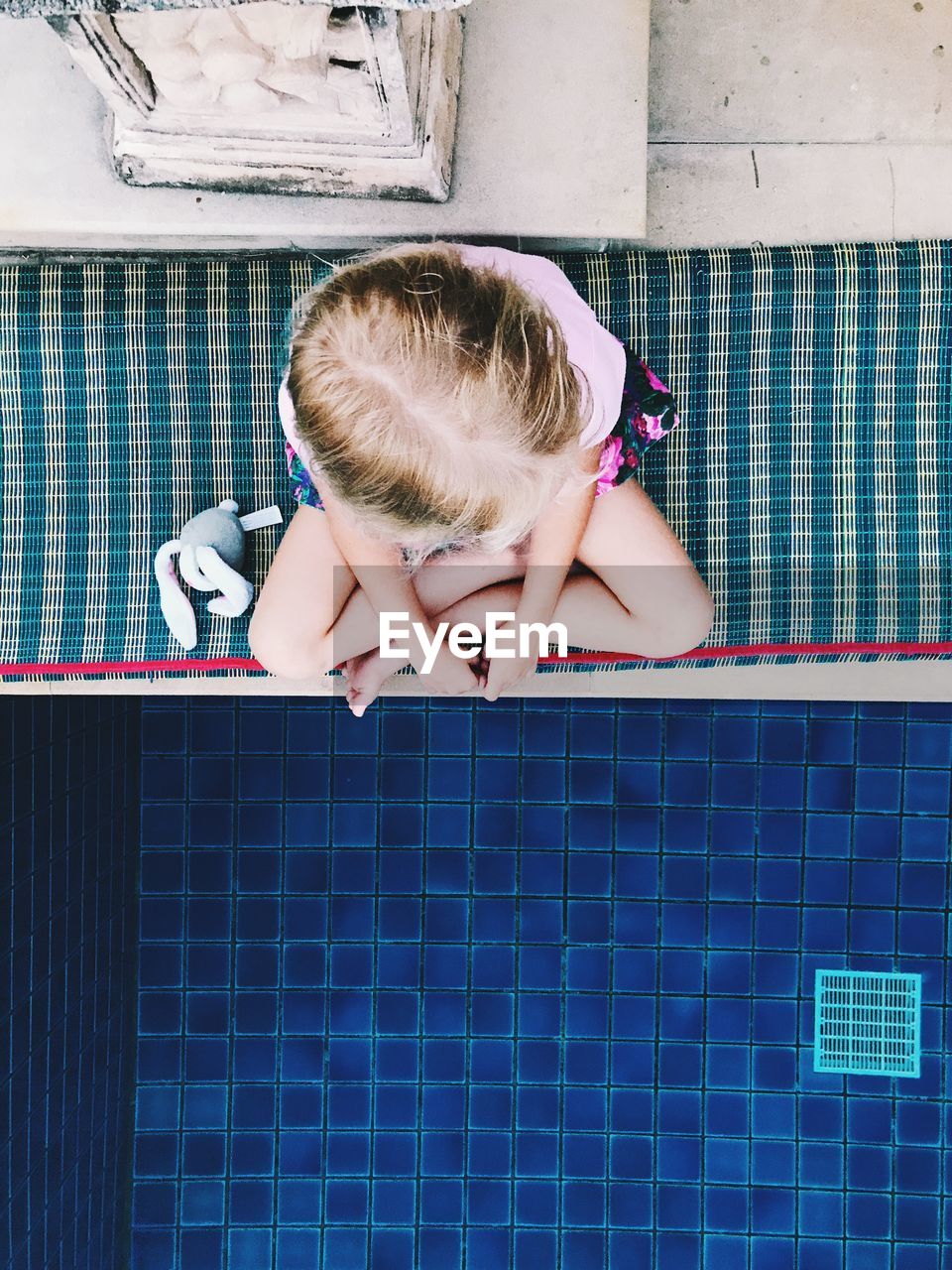 Girl sitting by swimming pool