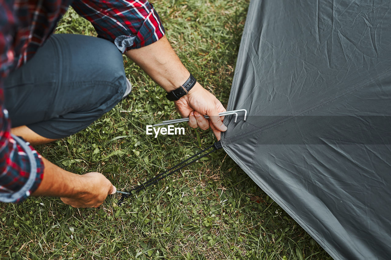 Man putting up a tent at camping during summer vacation. preparing campsite to rest and relax