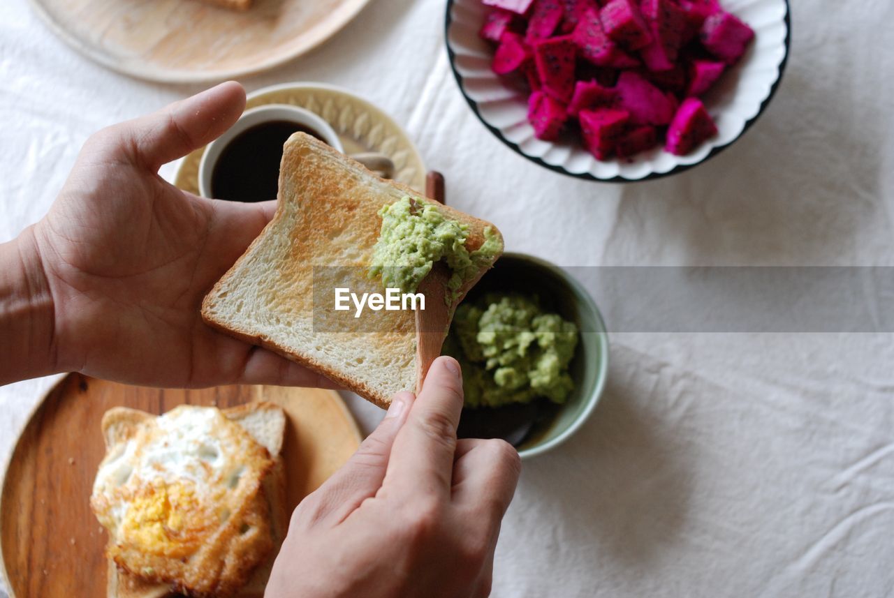 Cropped hand of person preparing breakfast on table