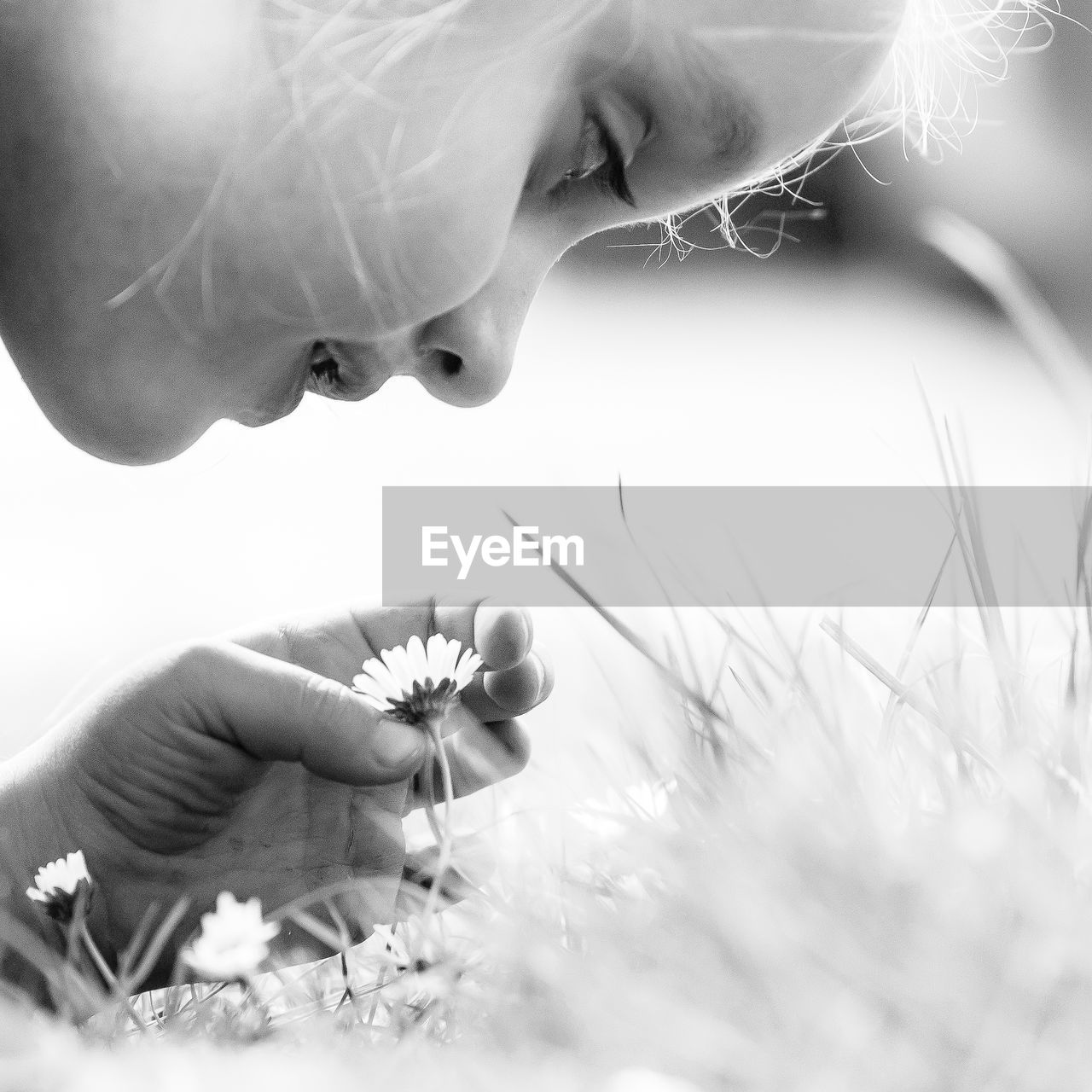 Close-up of girl looking at dandelion flower on field
