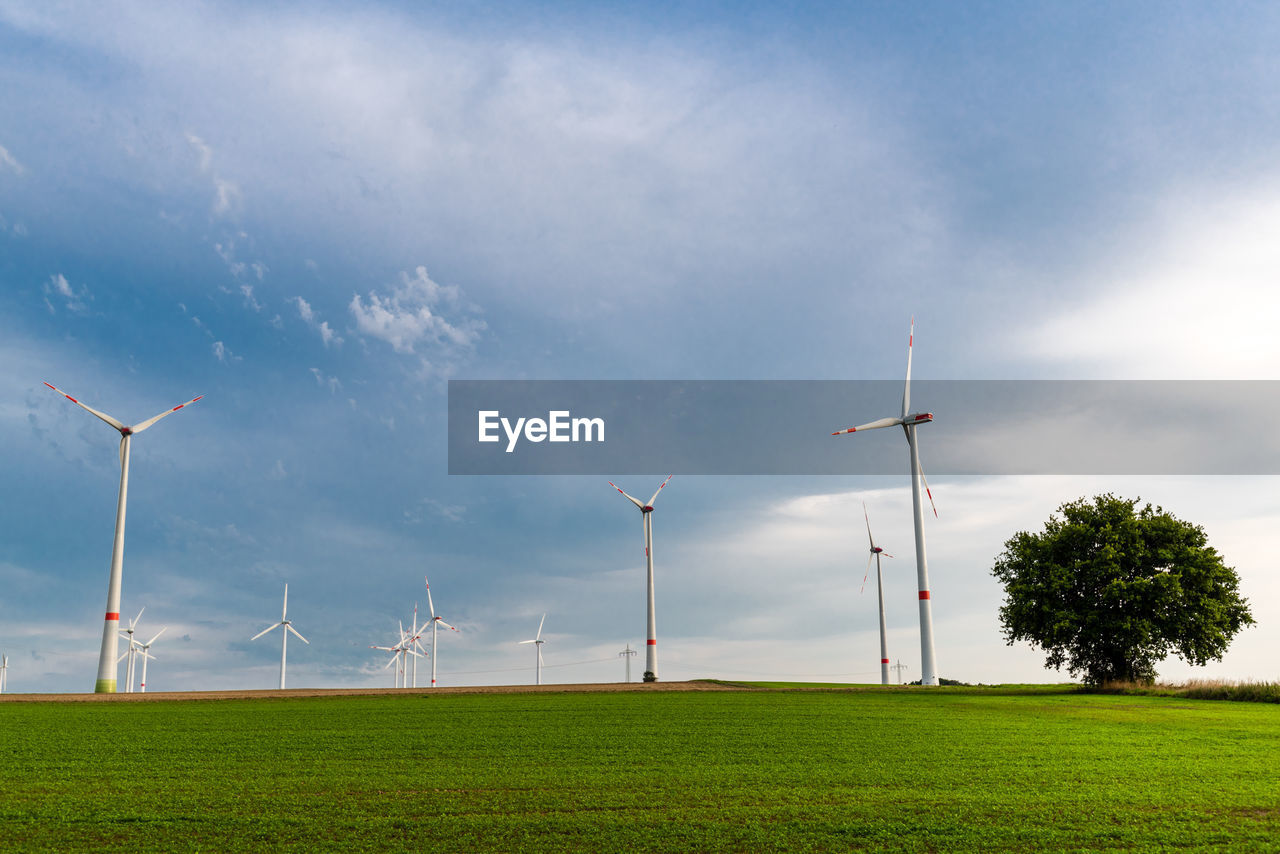 WIND TURBINES IN FIELD AGAINST SKY