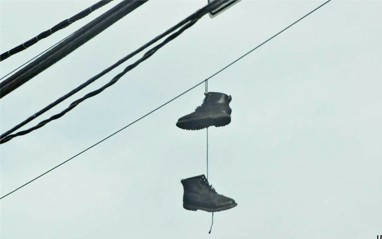 LOW ANGLE VIEW OF CABLES HANGING AGAINST SKY