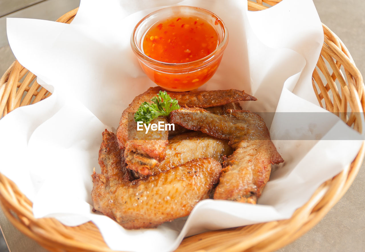 High angle view of fried chicken wings with sauce in basket