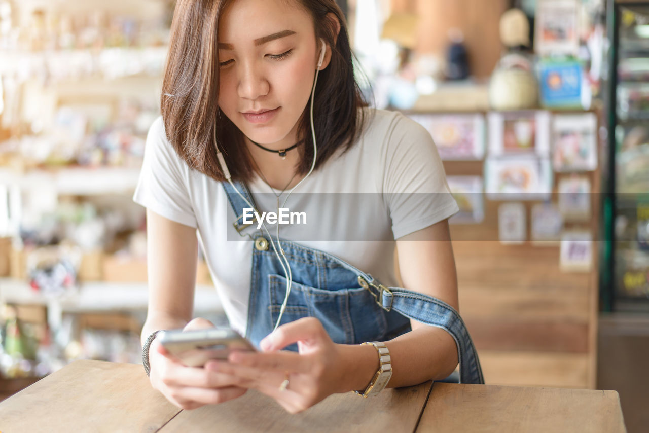 Woman using phone while sitting at table in cafe