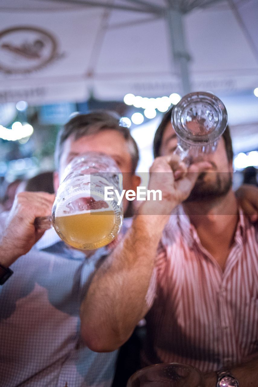 Close-up of friends drinking beer in bar