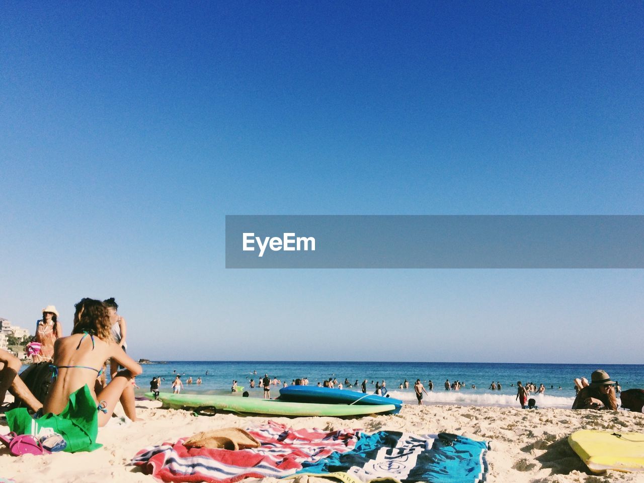 People at beach against clear blue sky
