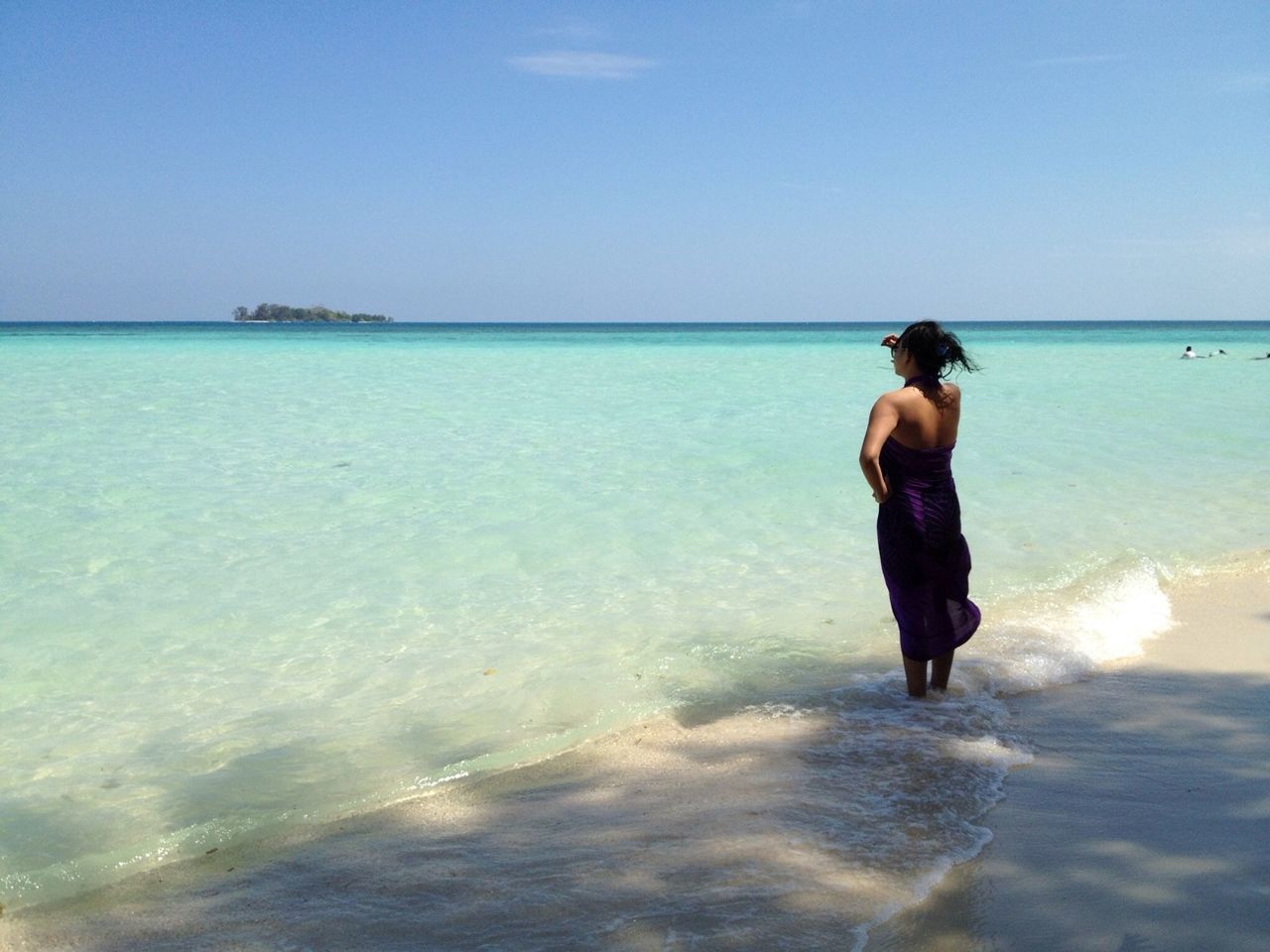 Rear view of woman standing on beach against clear sky