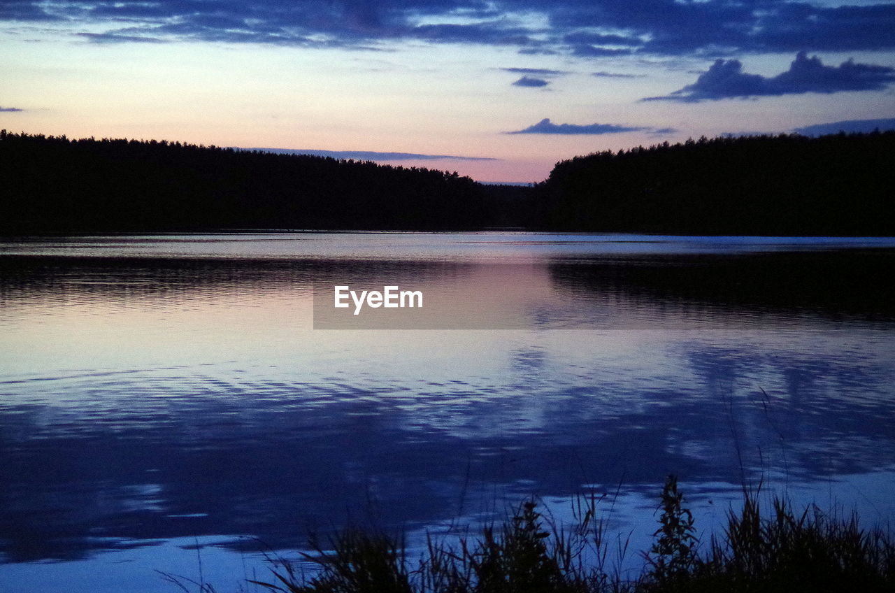 Scenic view of calm lake against cloudy sky