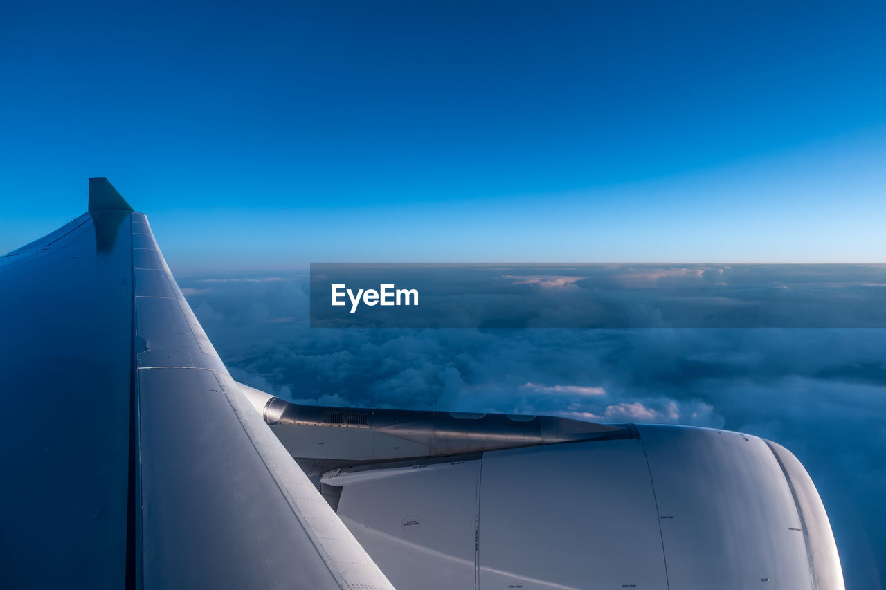 Cropped image of airplane against cloudy blue sky