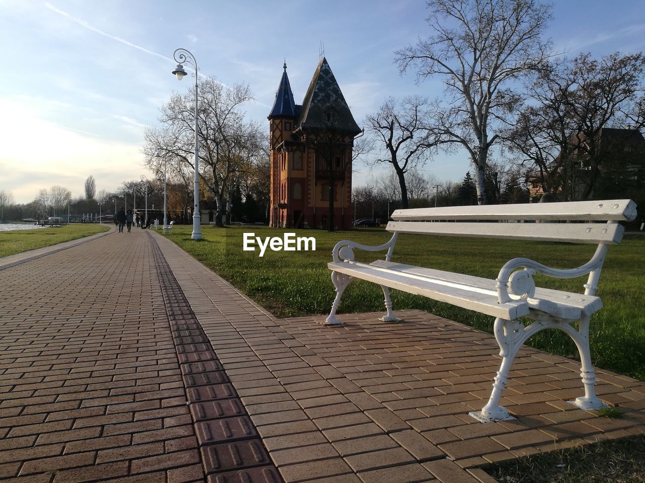 EMPTY BENCHES BY FOOTPATH AGAINST BUILDING